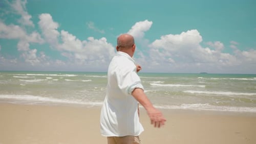 Asian elderly female holding husband hand and running on tropical beach to the sea on a holiday