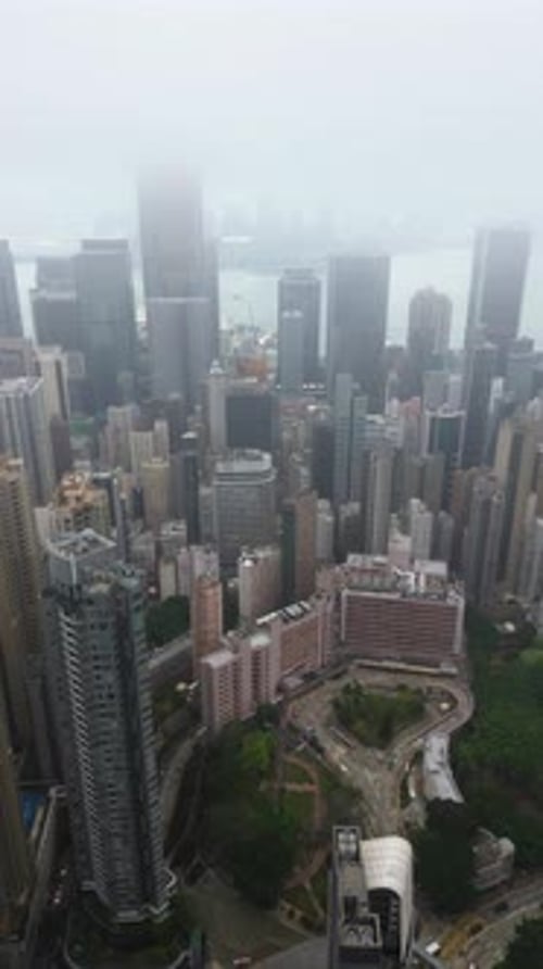 Vertical drone shot rotating over the central district of Hong Kong, foggy day