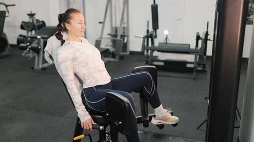 Mulher atlética treinando coxas na máquina abdutora