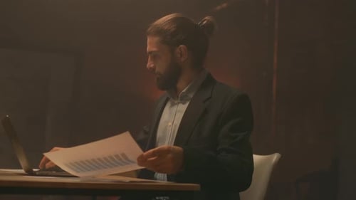 Man Analyzes Data on Laptop in Office at Night