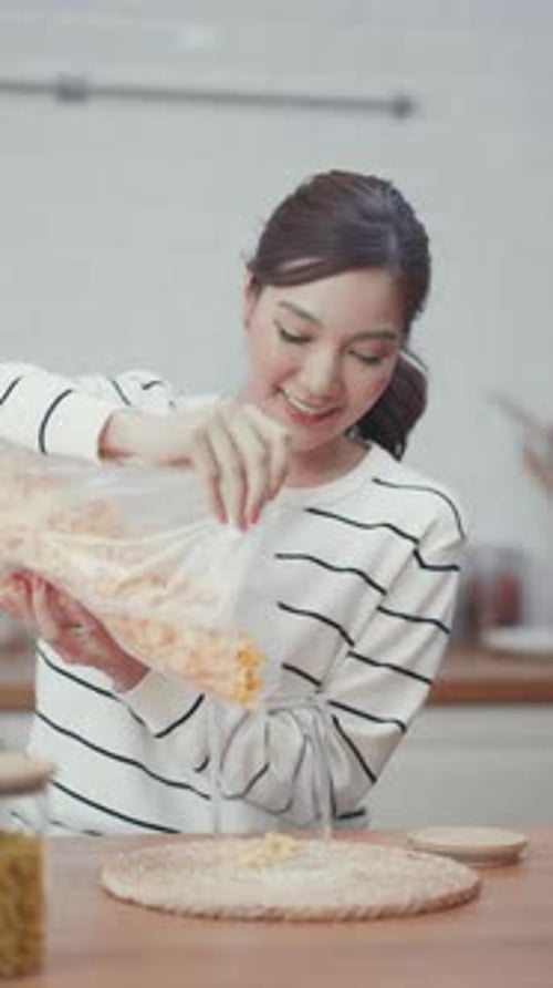 Woman Pours Pasta Into Jar on Kitchen Counter