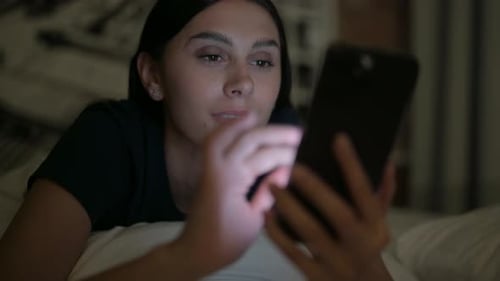 Close Up of Latina Woman using Smartphone at Night in Bed