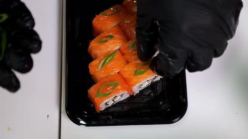 Closeup of a Chef Putting Green Onions on Sliced Sushi in a Restaurant