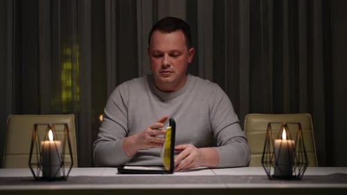 A Man Sits at a Table and Reads the Bible