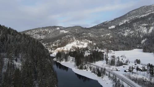 A River and a road along it in winter in Southern Norway. Drone footage