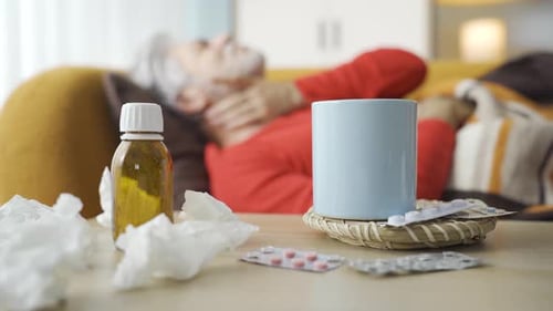 Sick Senior Man Resting on Couch with Medicine