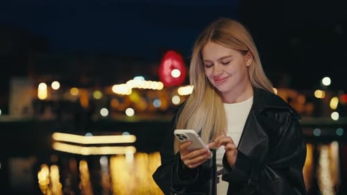 Woman Using Phone at Night in City