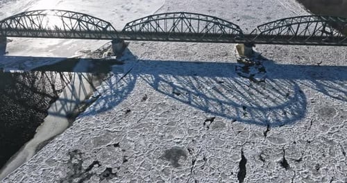 Traffic on bridge over a frozen river with ice floes.