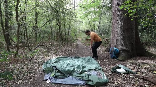 Slow motion of man setting up camping tent at a campsite in the woods