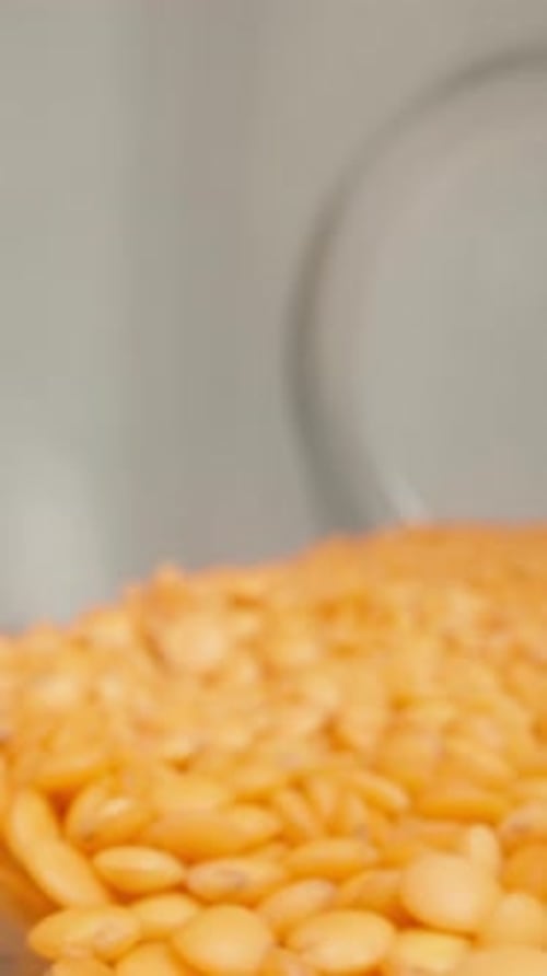 A glass jar of lentils fell onto the table and wobbles, while the camera zooms. Vertical video.
