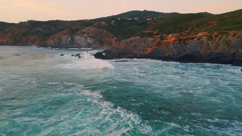 Sunset foamy waves washing rugged cliffs on a stunning volcanic ocean coastline