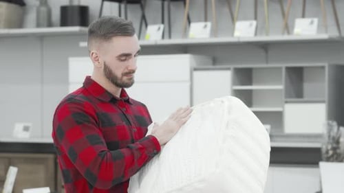 Handsome Man Exploring Orthopedic Mattress Options at a Stylish Furnishings Store