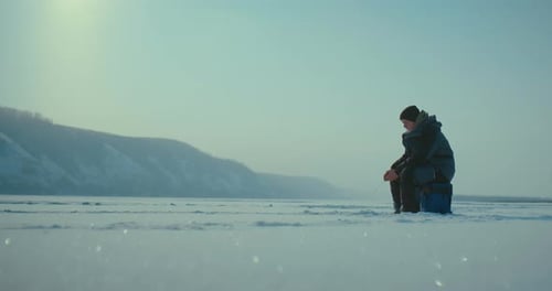 Lonely Fisher Catching Fish in Ice Hole in Beautiful Winter Day Getting Catch By Rod Prores