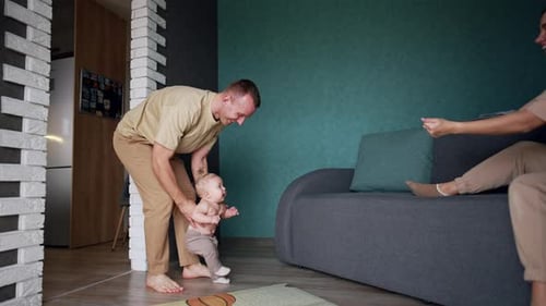Father Helps Infant Take First Steps at Home