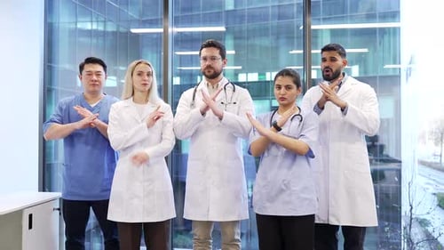 Grupo de médicos serios con los brazos cruzados, el signo X y la cabeza sacudiendo la cabeza sin ponerse de pie en la clínica del hospital.