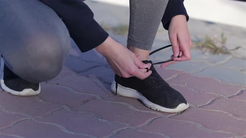 Young Sport Woman Tying Running Shoes During Training Outside