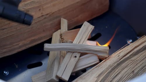 Ignited wood chips used to start a campfire, close-up video