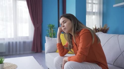 Sad Young Woman Sitting on Couch Indoors