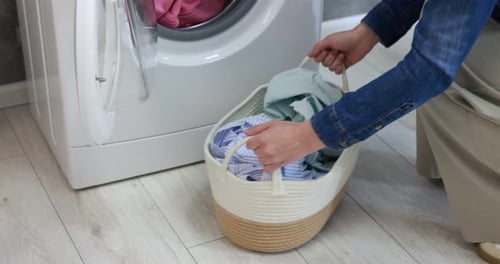 Woman putting different clothes onto drying rack indoors, closeup. Camera moving up