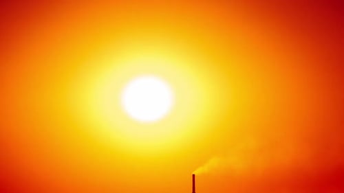 Puesta de sol en un cielo naranja claro sobre el horizonte con un lapso de tiempo de silueta de fábrica