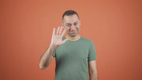 Man Waving Hello Against an Orange Background