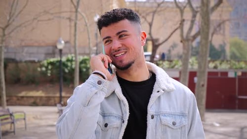 Young Adult Chatting on Mobile Phone in Park