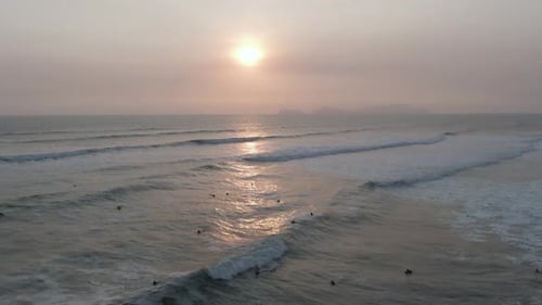 Sunset on a calm beach with people swimming