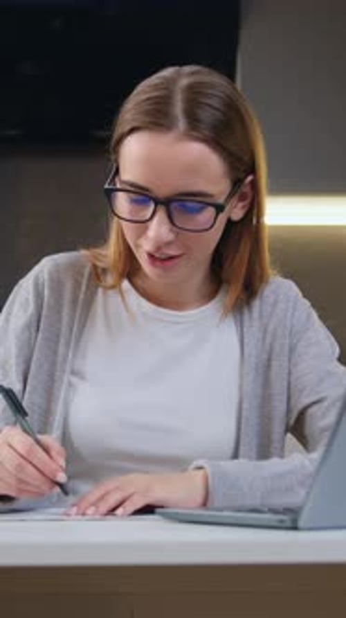 Woman Working from Home Using Laptop and Taking Notes