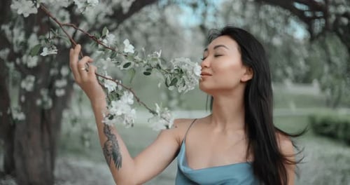 Young Woman Smelling Apple Blossoms in a Park