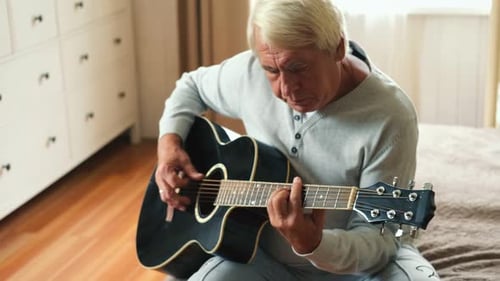 Senior Man Playing Acoustic Guitar at Home
