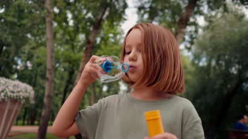 portrait beautiful cute little girl blowing soap bubbles in city park happy carefree childhood