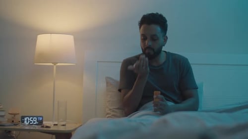 Adult Taking Pills at Night in Bedroom