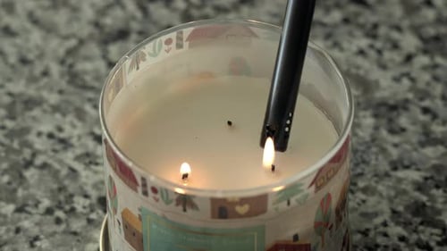 Close up as fall holiday candle on countertop is lit with a candle lighter, 4K