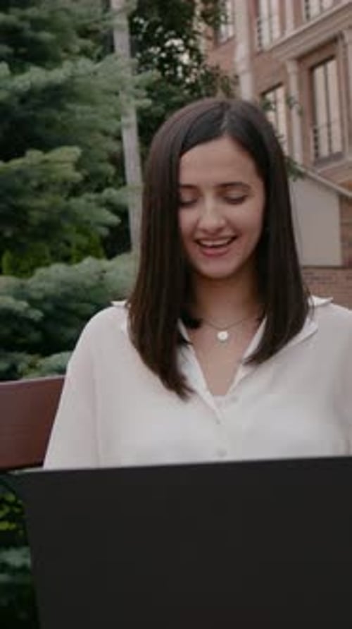 Woman Works on Laptop Outside in Urban Setting
