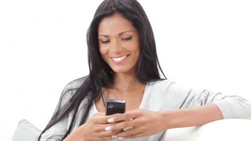 Smiling Woman Using Smartphone on Sofa Indoors