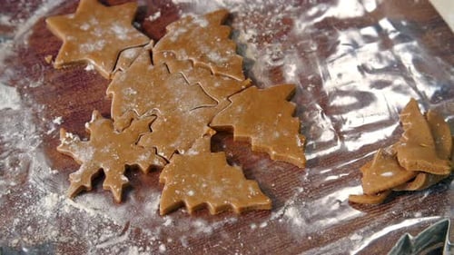 Cutting Christmas Cookie Shapes from Dough on Wooden Board