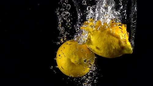 Fresh Lemons Splashing Into Water on Black Background