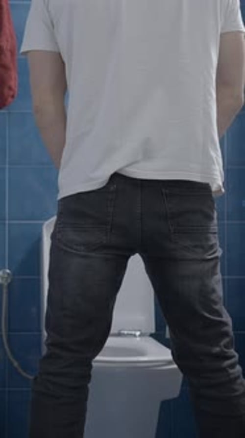 Man standing in bathroom, facing toilet
