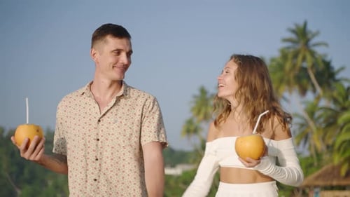 Pretty Woman Talks to Boyfriend Walking on Tropical Beach Smiling Couple Enjoy Holidays Drink