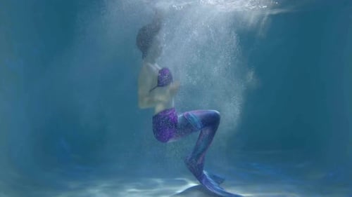 Anmutige schlanke hübsche Frau im Meerjungfrauenkostüm, die sich unter Wasser hinlegt