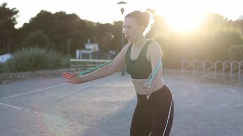 Woman Exercising with Elastic Band at Sunset