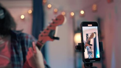 Young Adult Playing Guitar and Recording Video