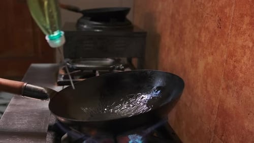 Close-up of a concave hot cast-iron frying pan, generously watered with vegetable oil
