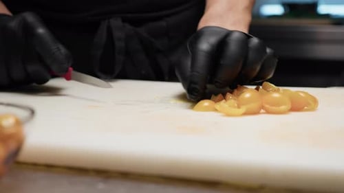 Chef Slicing Cherry Tomatoes in Commercial Kitchen