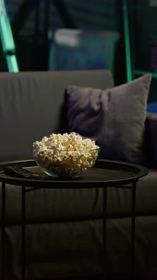 Vertical Video Bowl of Popcorn on Table in Empty Neon Lit Cozy Residential Interior
