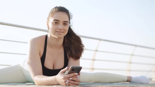 Woman Doing Splits Using Smartphone Outdoors