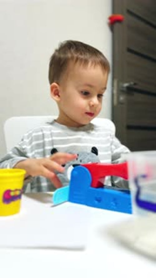 Bebé jugando con juguetes de colores. Niño lindo y juguetón con juguete de plástico. Vídeo vertical.