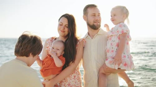 Family Enjoying a Sunny Day at the Beach with Children Playing and Smiling By the Ocean Shore