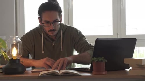 Young Adult Writing at Desk with Laptop
