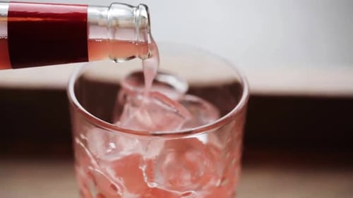 Pouring Pink Soda into Glass with Ice